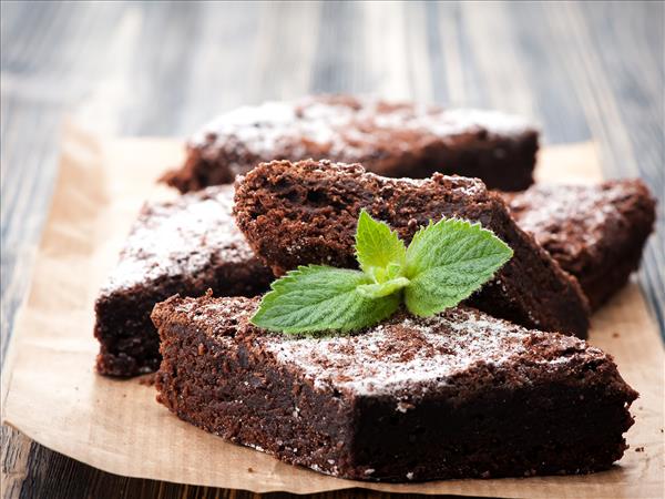 Chocolate brownies dusted with icing sugar and garnished with fresh mint leaves