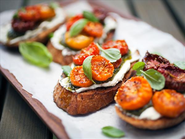 Toasted crostini topped with roasted cherry tomatoes, fresh basil and soft cheese