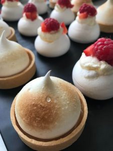 Mini lemon meringue tarts topped with toasted meringue and fresh raspberries
